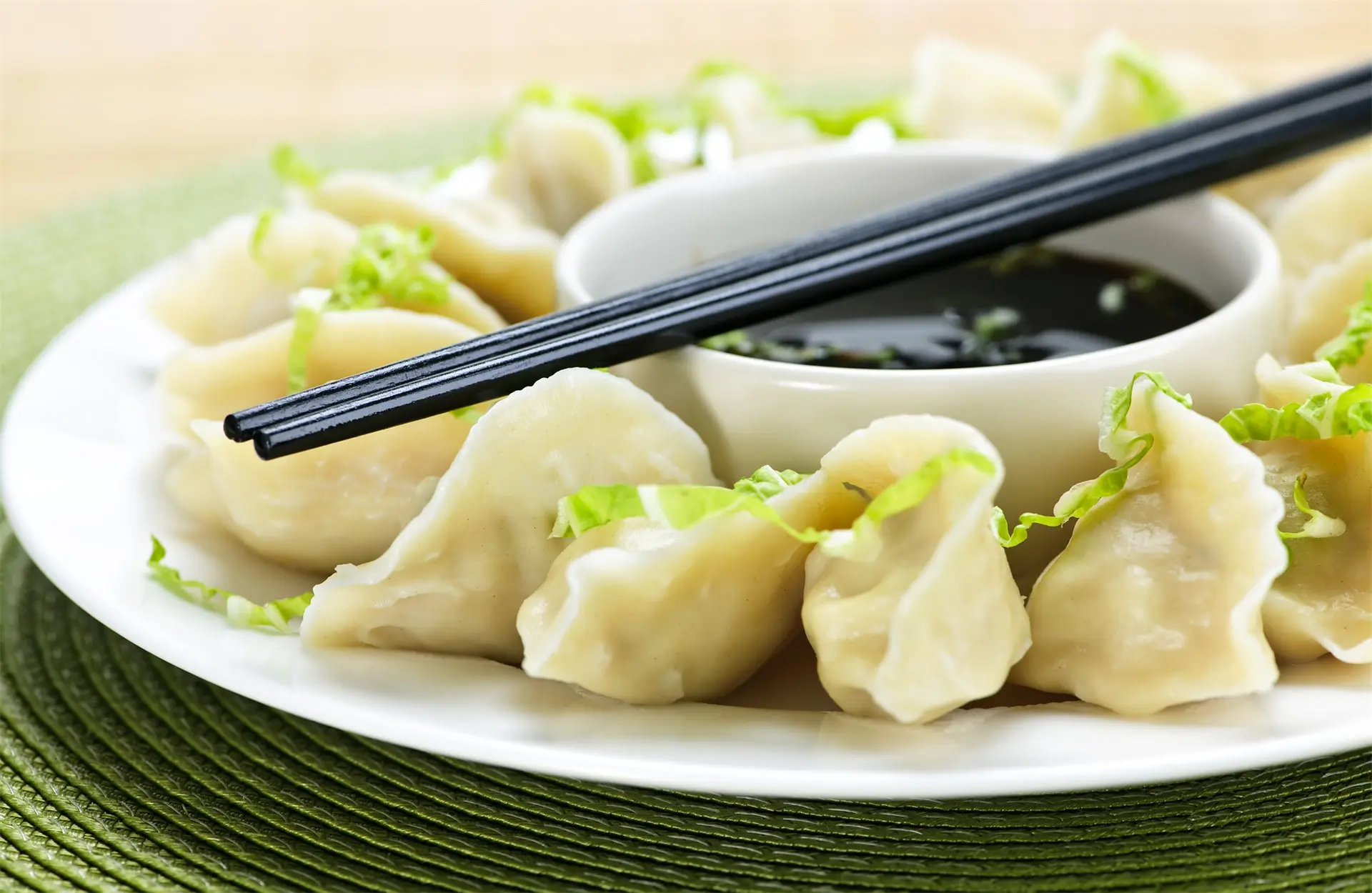 Steamed dumplings on a white plate with vinegar and black chopsticks at Yum Dumpling，a Chinese Restaurant in Orange